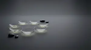 Seven clear glass bowls with stones are illuminated by light on a dark background.