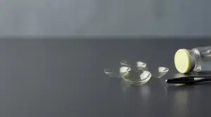 Four contact lenses and a contact lens bottle on a table