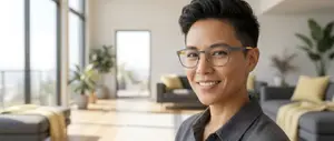 Man in glasses standing in a living room with couches and plants