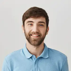 A man with a beard is smiling and wearing a blue polo shirt.