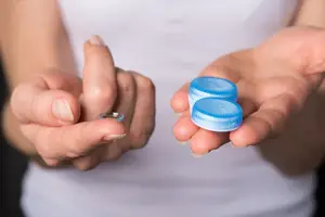 A person holding a blue bottle and a silver ring on their finger