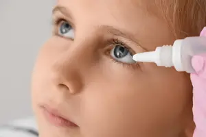 A young girl using eye drops