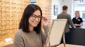 woman in a glasses store with a reflection of her in a mirror