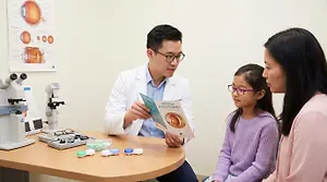 An eye doctor discusses myopia management with a child and her mother.