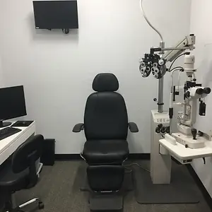 An empty optical examination room with chairs and monitors in the corner