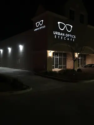 Urban Optics Eyecare building at night with white logo on the front