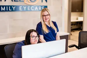 Two women working in an office with a sign reading Family Eyecare