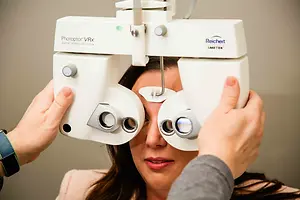 A woman getting her eye examined by a doctor using a Phoroptor VRx Reichert instrument