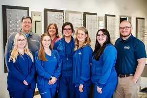 A group of people in blue outfits are posing for a photo in an indoor area
