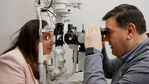 A man examining a woman's eyes using an ophthalmoscope.