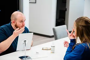 An adult man and woman are sitting in front of a table in what appears to be a hospital room.