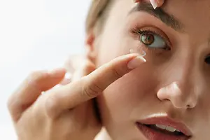 Close up of a woman wearing contact lenses and applying makeup.