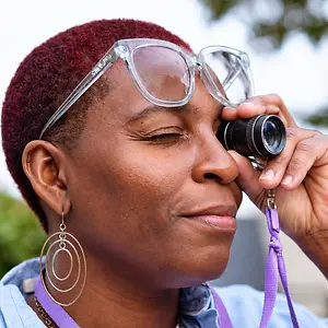 Close-up of a woman wearing glasses while looking through an eye examination lens