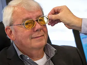 Optometrist adjusting tinted glasses on an older man