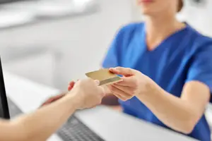 A doctor accepting a credit card from a patient.