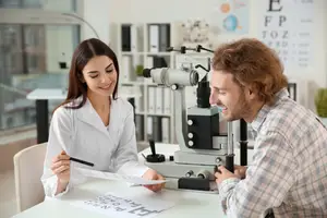 A man is checking his eyesight with an optometrist in a clinic.
