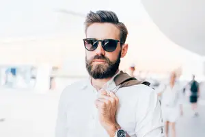 Man with beard and sunglasses standing in a public space