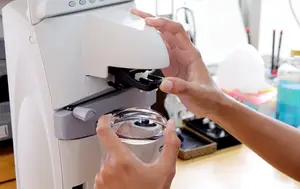 A person using a machine to process a glass sample in a lab
