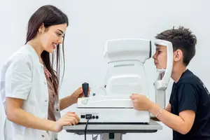 A woman optometrist is adjusting the phoropter on a young boy's eye