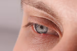 A close-up of a person's eye with a red spot on the eyelid.