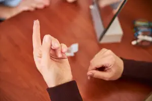 A person is trying on a contact lense and showing it to another person on a table