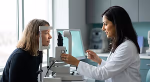 A woman is getting her eye examined by an eye doctor in a white coat