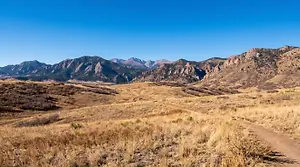 A view of a grassy field with mountains in the distance under a clear blue sky.