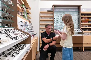 A man and a young girl are looking at glasses in a shop.