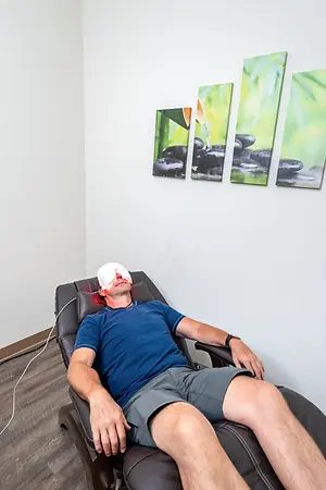 Man in a recliner wearing a red light facial mask