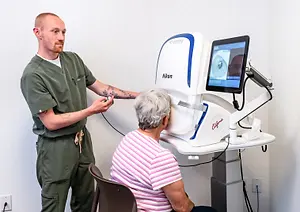 A man is examining a woman's eyes with a Nikon device