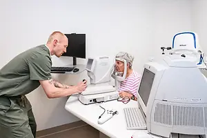 An optometrist is adjusting the equipment of an elderly woman in an office