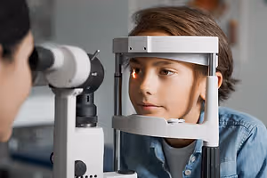 A young boy is undergoing an eye examination by a doctor in a clinic.
