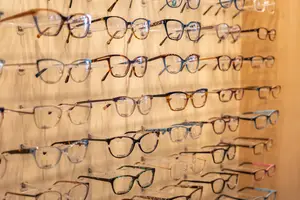 Several pairs of eyeglasses are displayed on a wall with a wooden background.