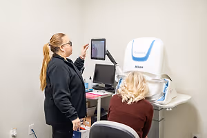 A woman is being examined by another woman using a Nikon device in a room.