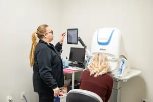 A woman is being examined by another woman using a Nikon device in a room.