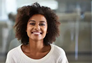 portrait of smiling african american woman in white sweater with curly hair