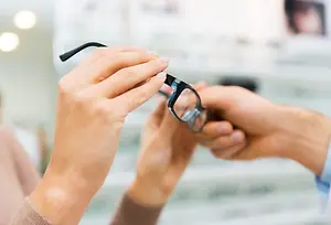 two hands adjusting a pair of glasses