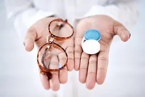 A person holds a pair of eyeglasses and a lens case in their hands