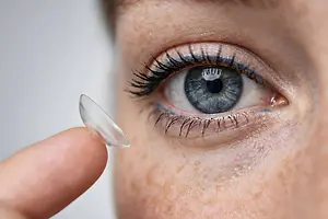 Close up of a woman wearing a contact lens and adjusting it with her finger
