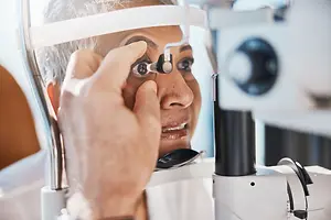 Optometrist examining an older patient's eye with a slit lamp