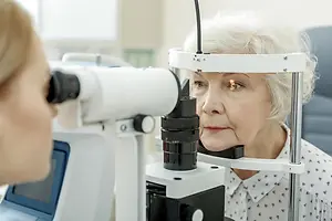 Older woman undergoing an eye examination with a slit lamp in an optometry clinic