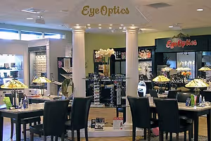 The interior of an Eye Optics shop with several black chairs, tables, and lamps, along with some decorative items.