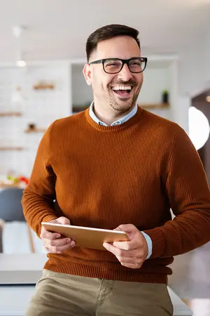 man smiling while looking at a tablet in a kitchen