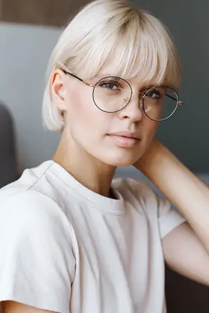 Woman with short blonde hair wearing glasses and a white shirt, posing for a photo.