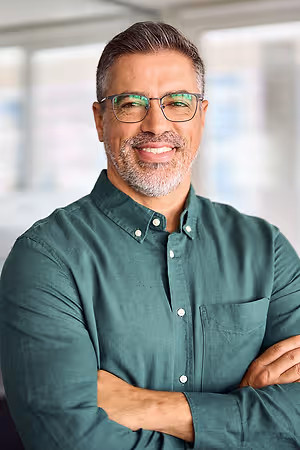 A man wearing a green shirt and glasses smiling at the camera