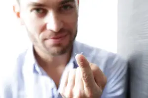 Man wearing a white shirt adjusting his contact lens