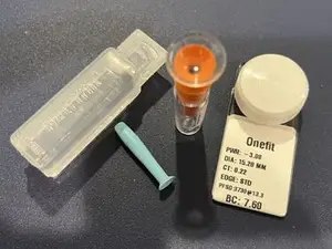 A set of medical tools including a syringe and a vial are displayed on a dark surface