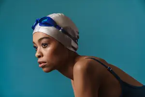 A woman wearing goggles and a swim cap standing in a pool
