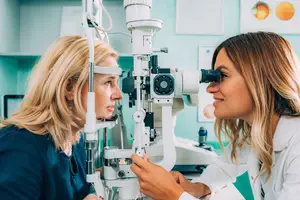 A woman is having her eyes examined by an optometrist in a medical room