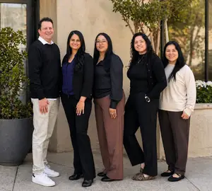 A smiling group of people stand together outside an office building